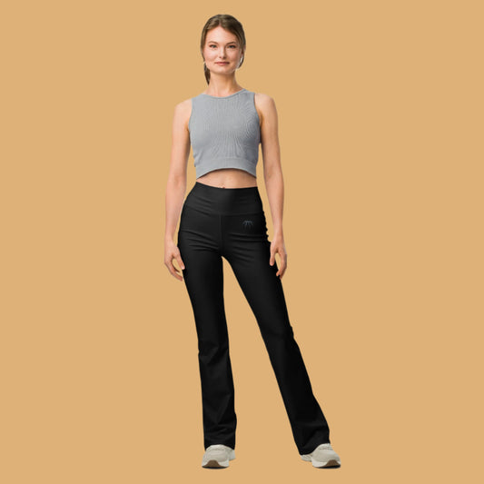 Woman wearing a gray sleeveless top and black pants on a beige background