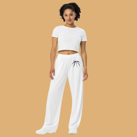 Woman wearing a white crop top and white pants with a black design on a beige background