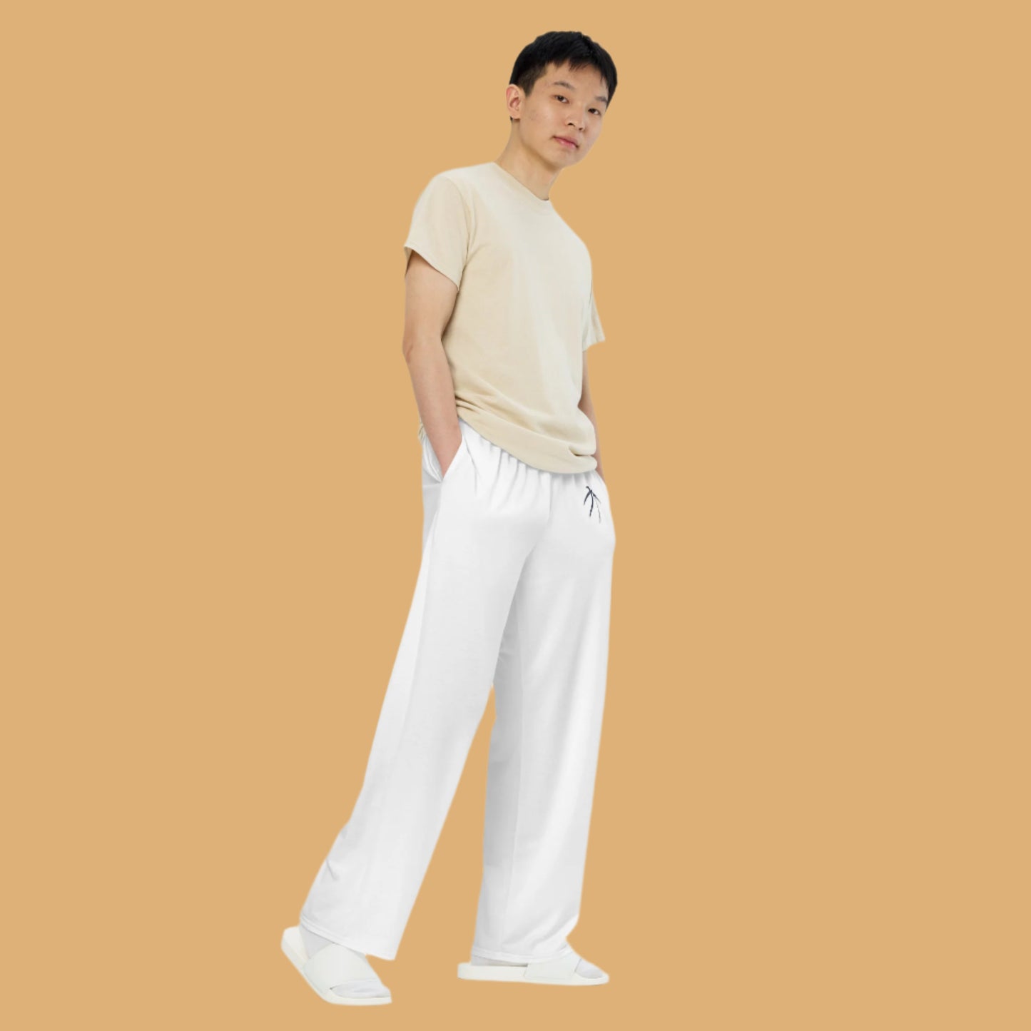 Person wearing a beige shirt and white pants on a beige background
