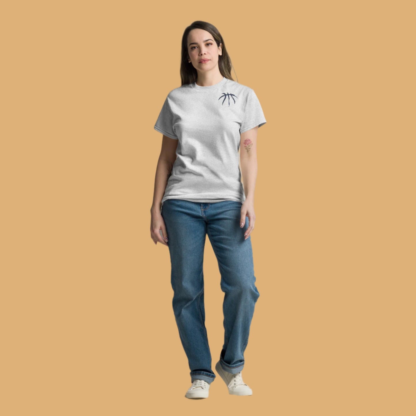 Woman wearing a white t-shirt and blue jeans standing against a plain background