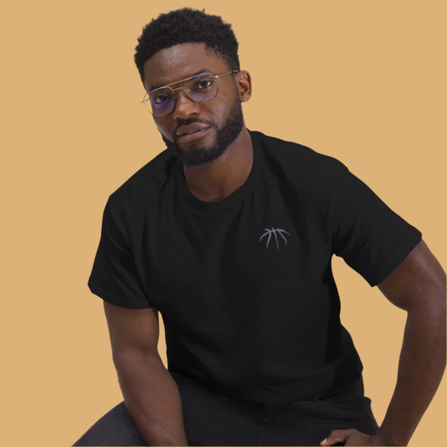 Man wearing a black t-shirt with a logo on a beige background
