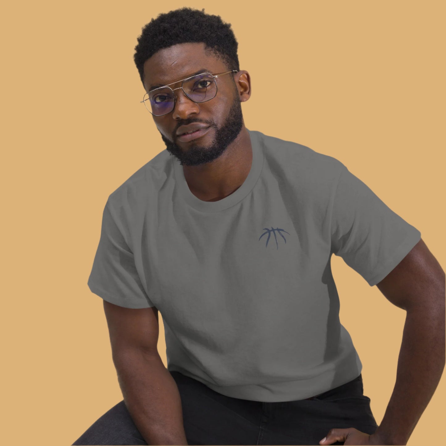 Man wearing a gray t-shirt with a small logo on a beige background