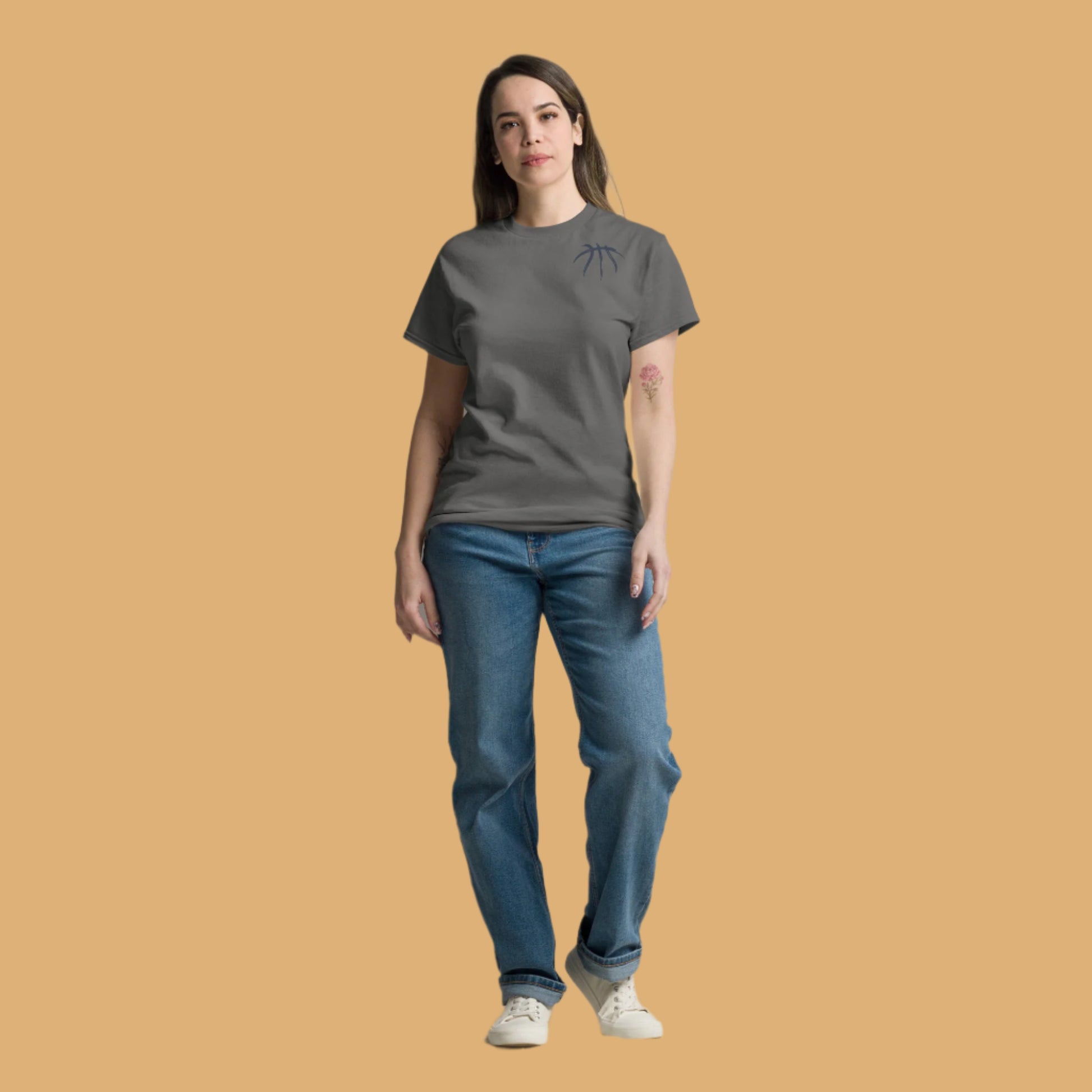 Woman wearing a gray t-shirt and blue jeans on a beige background