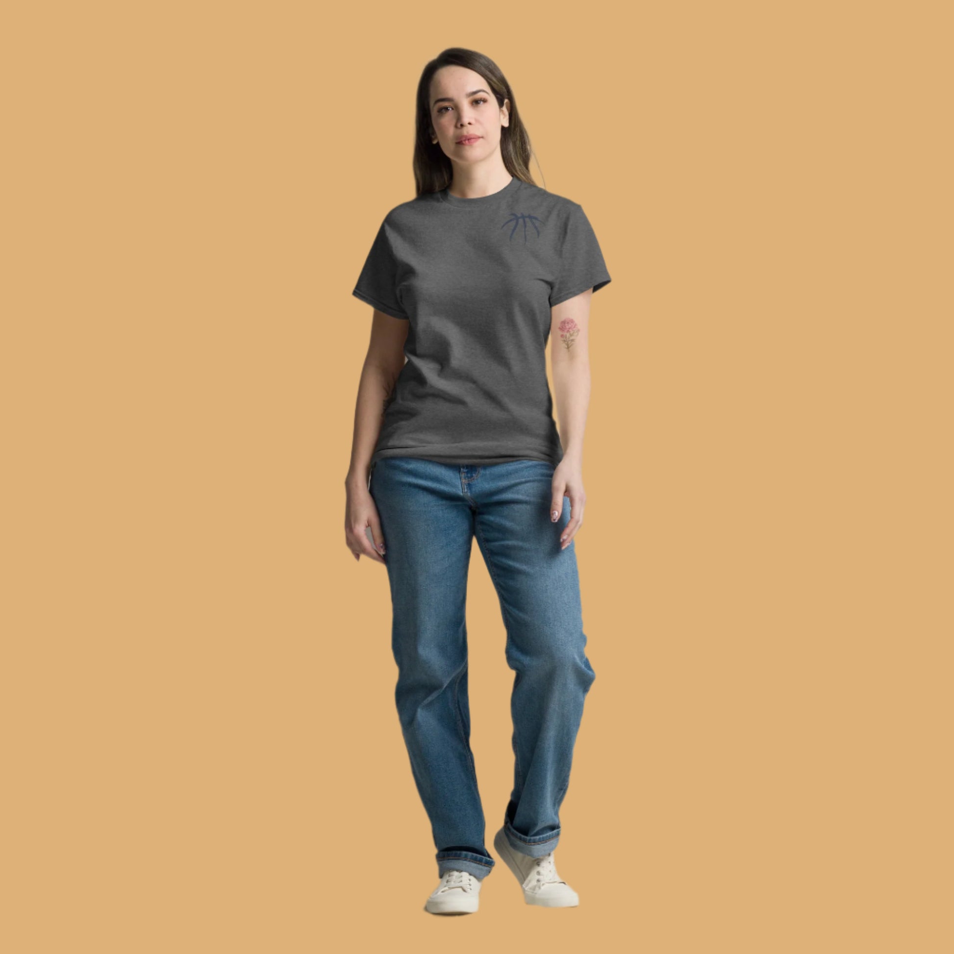 Woman wearing a dark gray t-shirt and blue jeans on a beige background