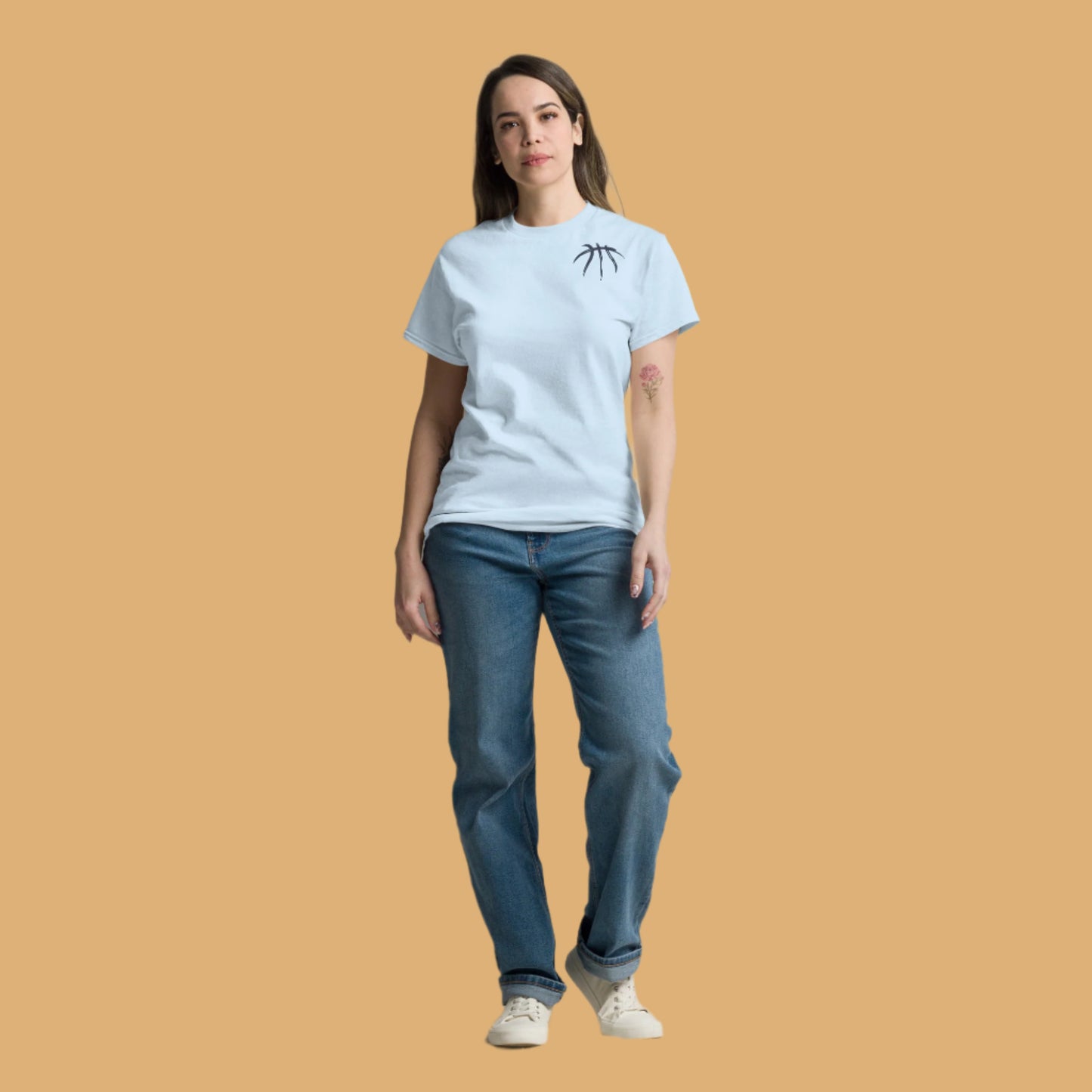 Woman wearing a light blue t-shirt and jeans standing against a plain background
