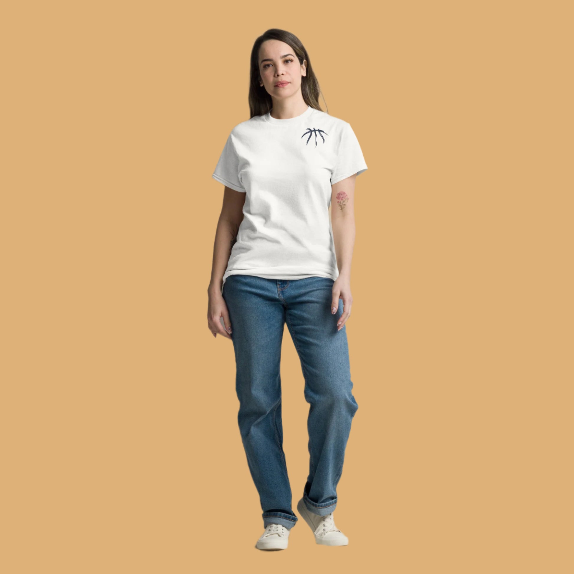 Woman wearing a white t-shirt with a black design and blue jeans against a plain background