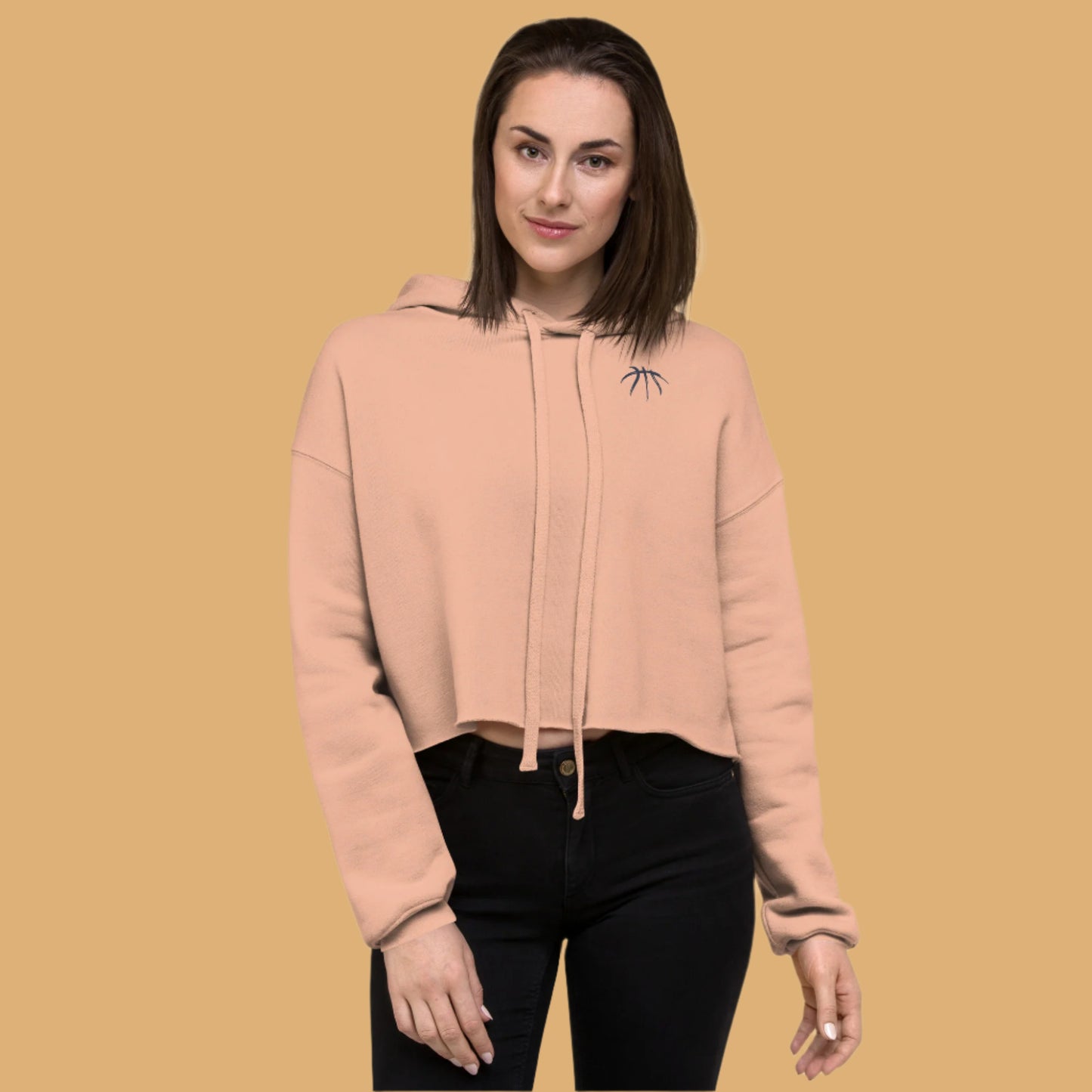 Woman wearing a beige hoodie with a small logo on a white background