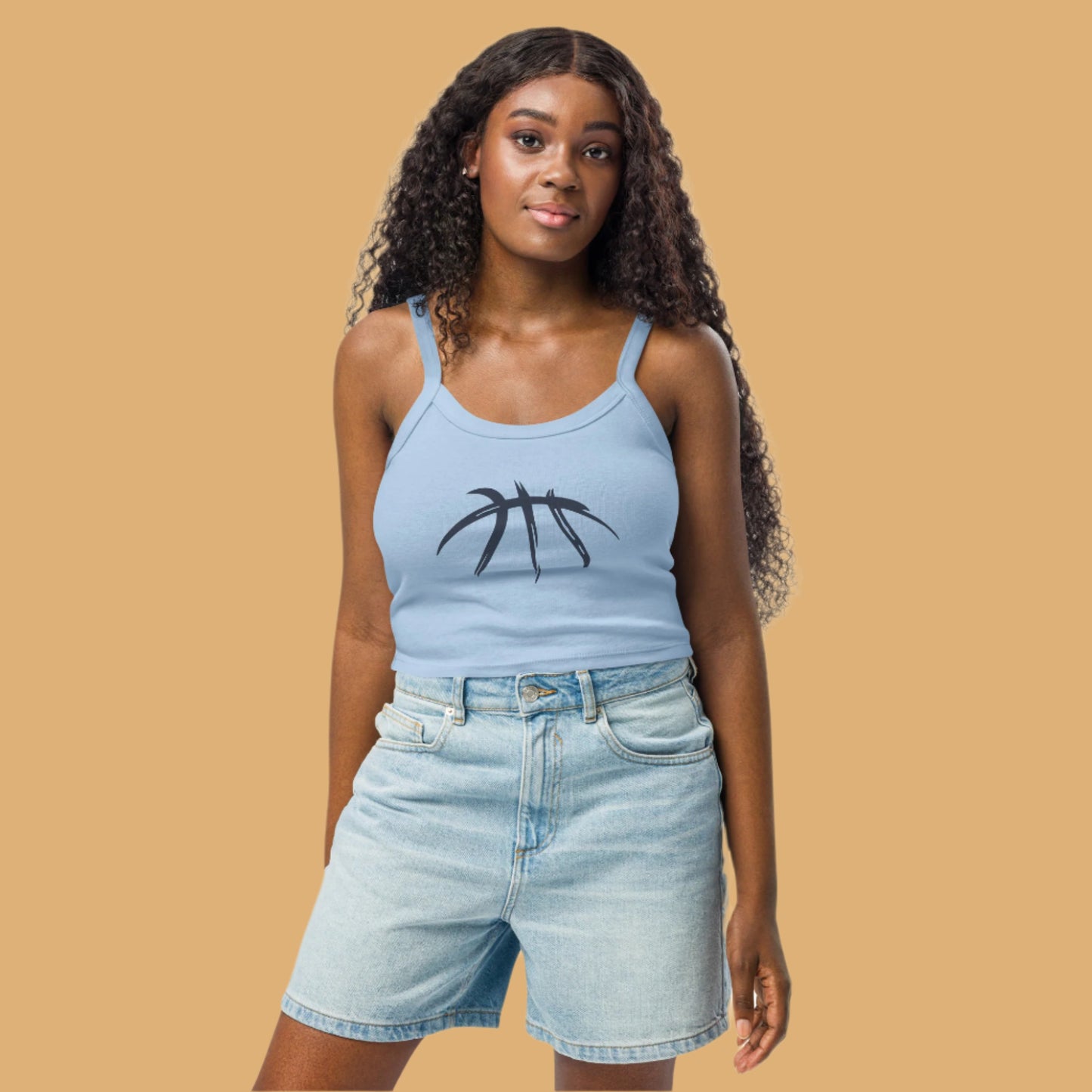 Woman wearing a light blue tank top with a graphic design and denim shorts on a white background
